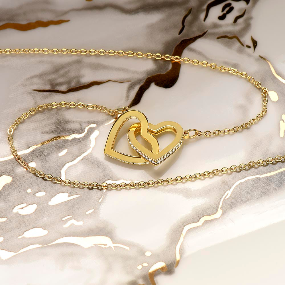Gold interlocking hearts necklace with chain on white fabric