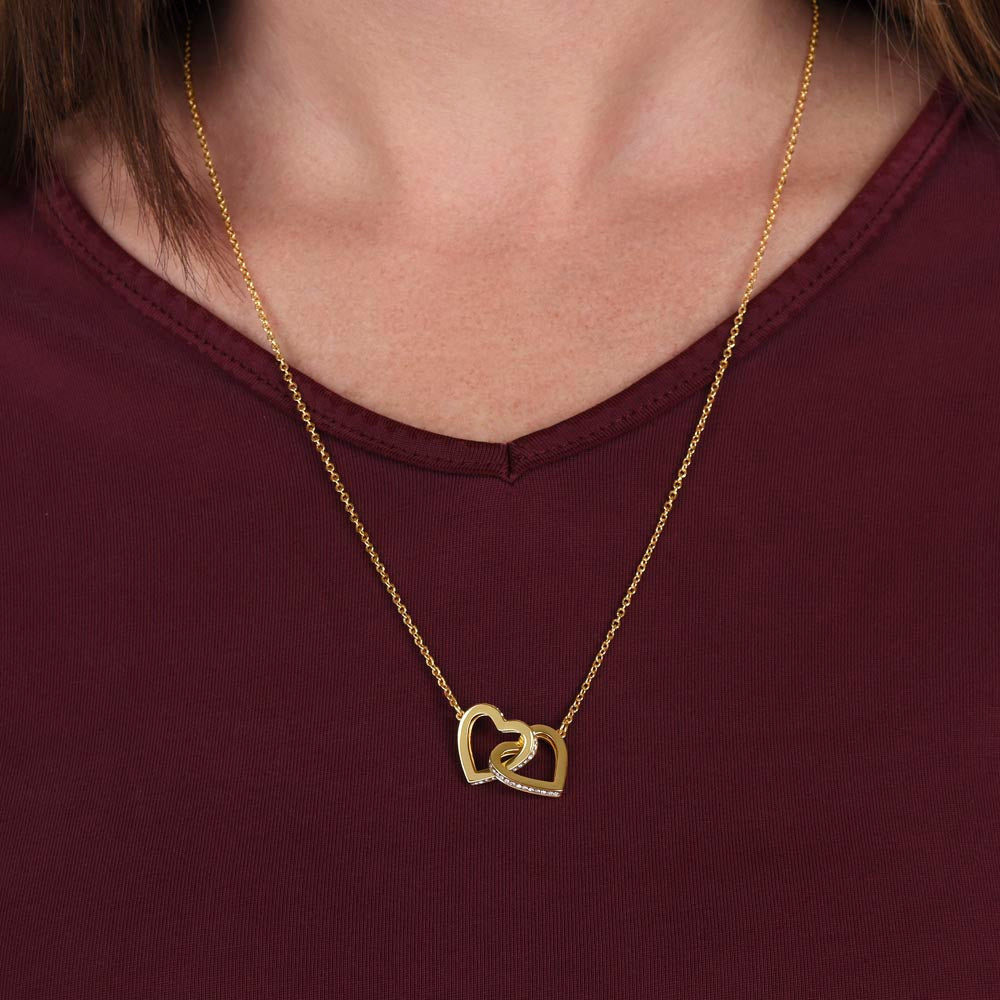Gold-tone heart pendant necklace on maroon shirt neckline