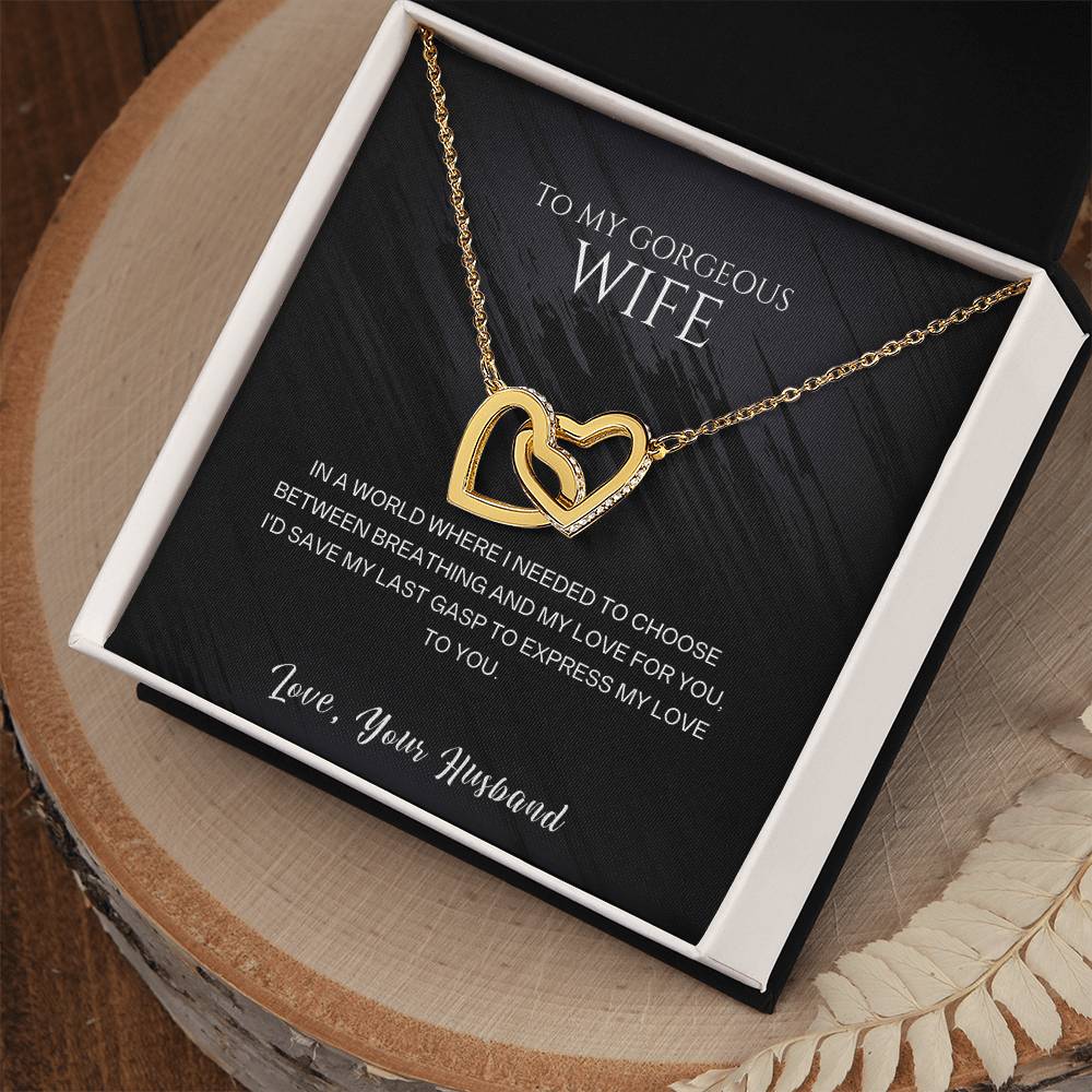 Gold-tone heart pendant necklace inside an open gift box on a wooden tray.