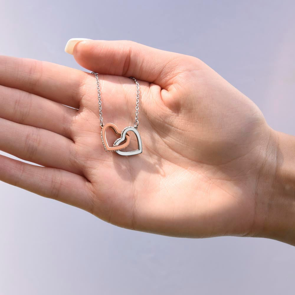 Heart pendant necklace with silver chain and rose-gold outline, worn on hand