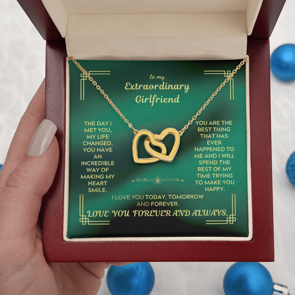 Gold heart interlocking pendant necklace displayed in a red gift box