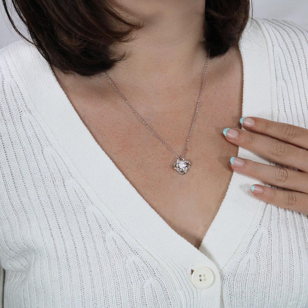 Love knot necklace with silver-tone chain and small round crystal pendant on neck