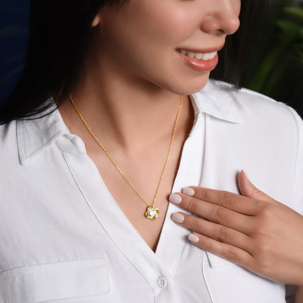 Love knot necklace with gold-tone chain and round crystal pendant on white shirt
