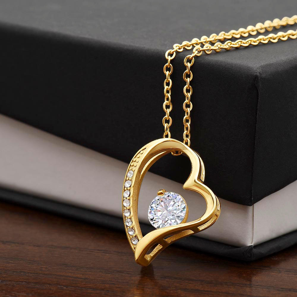 Gold-tone heart pendant necklace with round center stone and side pave detailing.