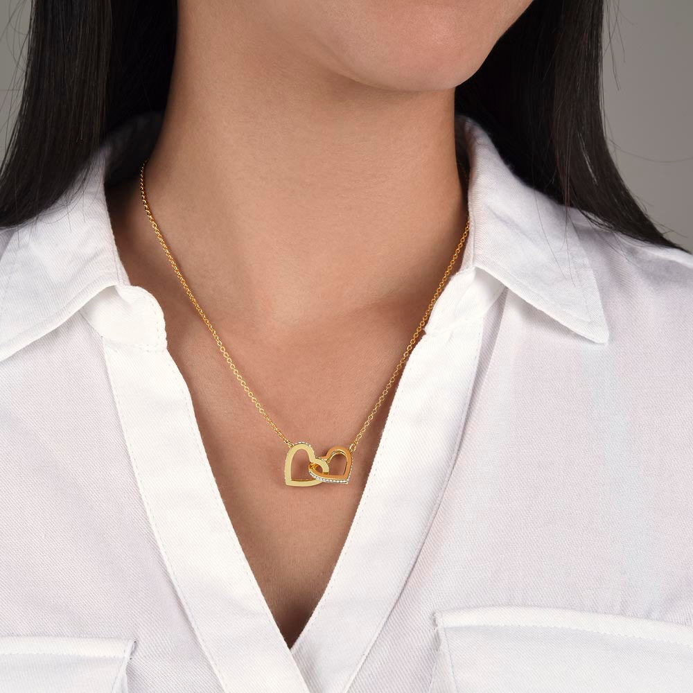 Gold-tone interlocking hearts necklace on fine chain worn at the neck