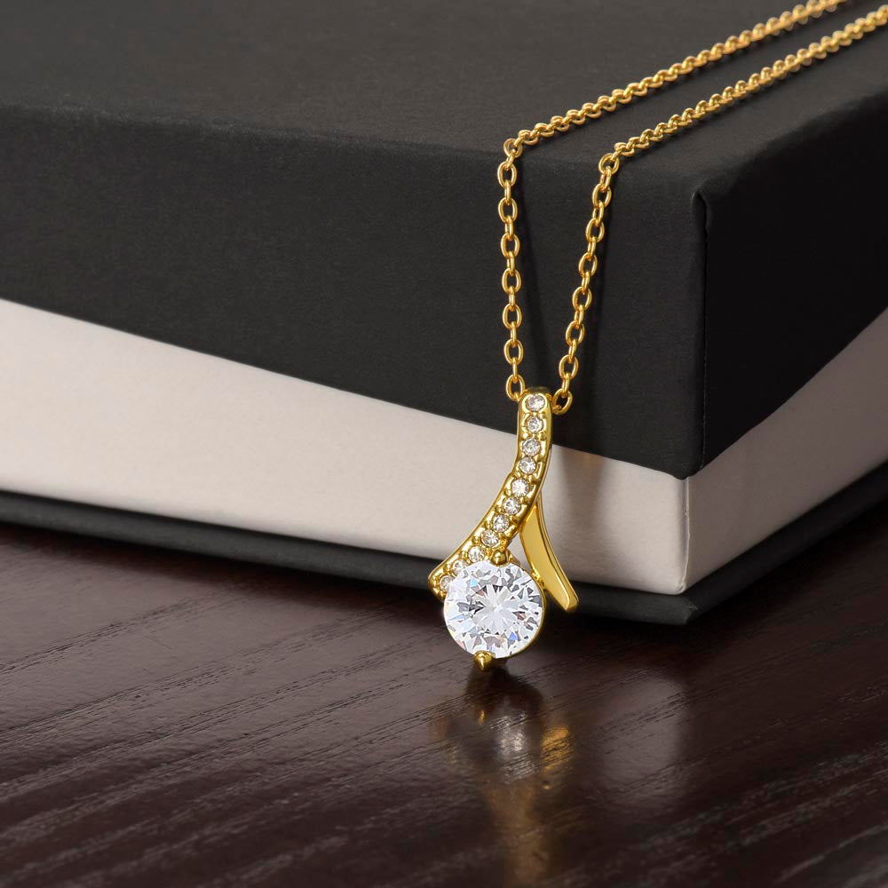 Gold-tone necklace with teardrop pendant, round sparkling stone, and pavé accents
