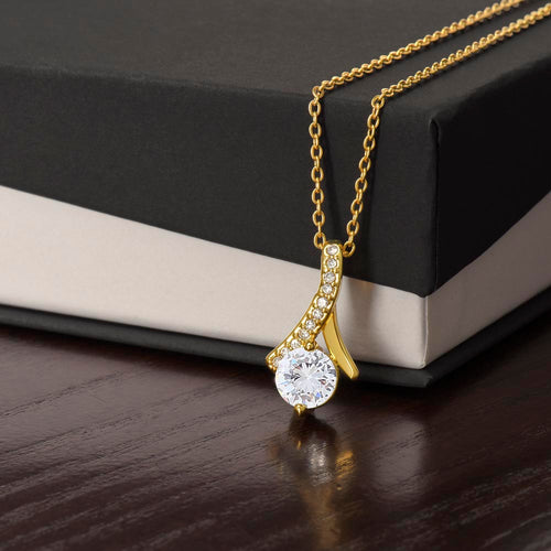 Gold-tone necklace with teardrop pendant, round sparkling stone, and pavé accents