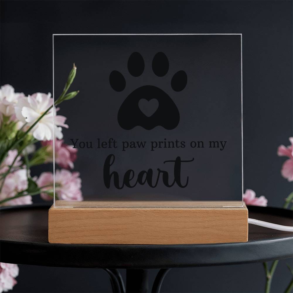 Clear acrylic keepsake with paw-print heart design and wooden base on dark setting