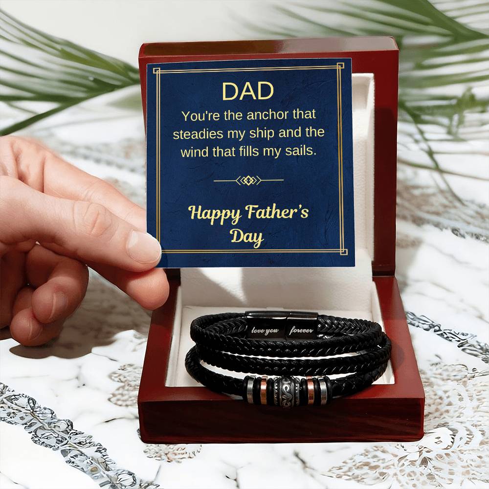 Braided black bracelet with metal bead accents held above red gift box