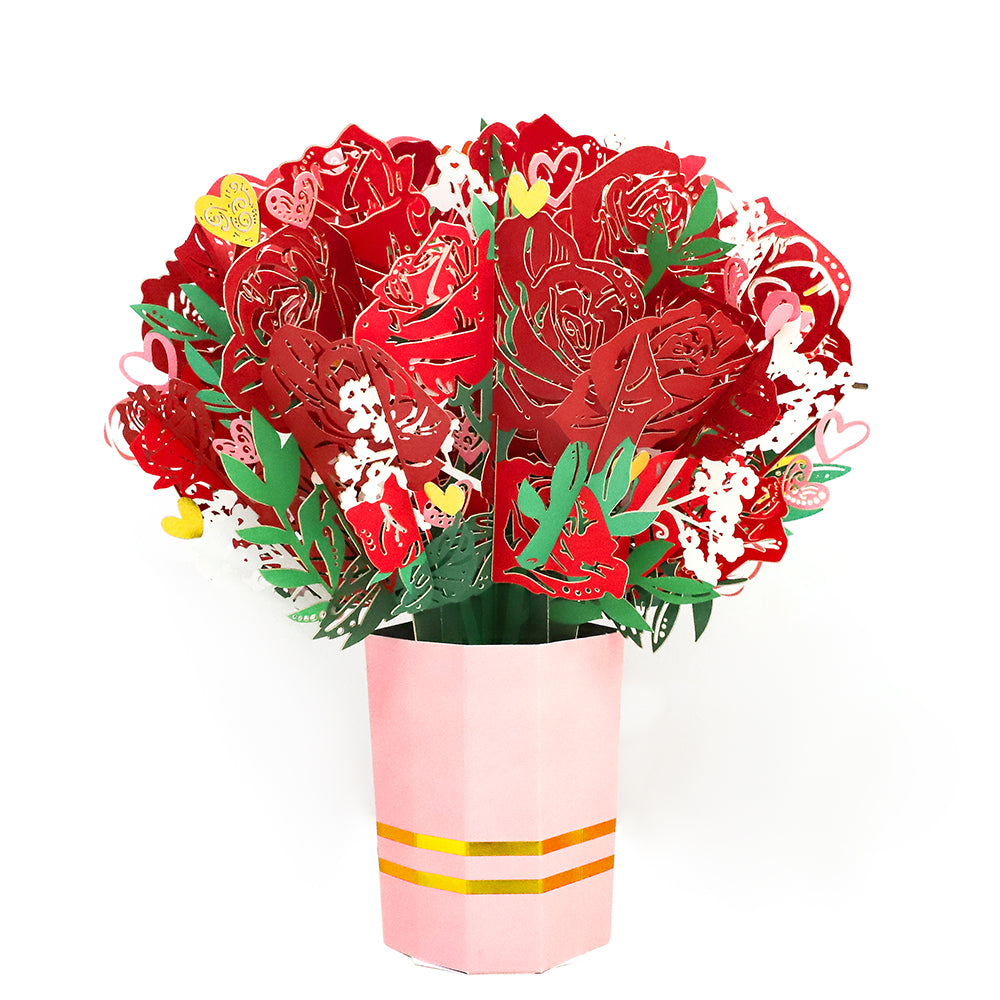 Red paper flower bouquet with green leaves and yellow accents in pink striped vase