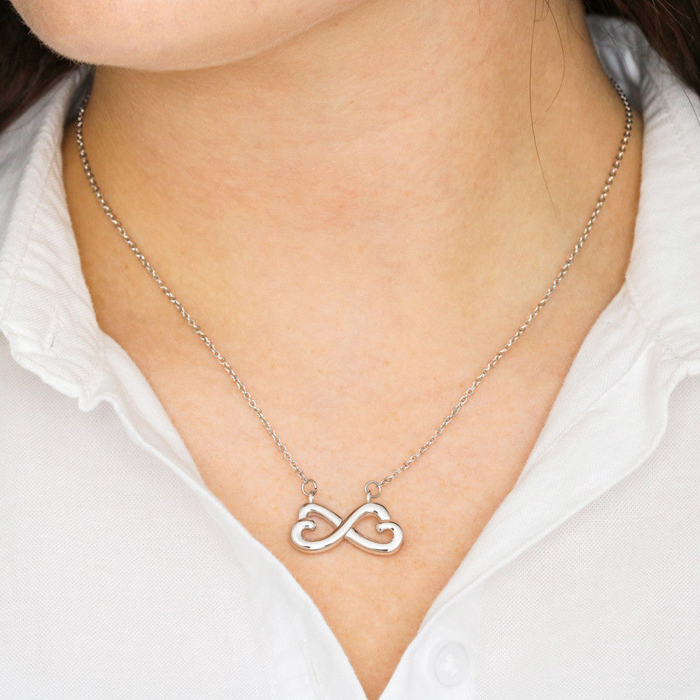 Silver-tone infinity heart pendant necklace worn on neckline, thin link chain