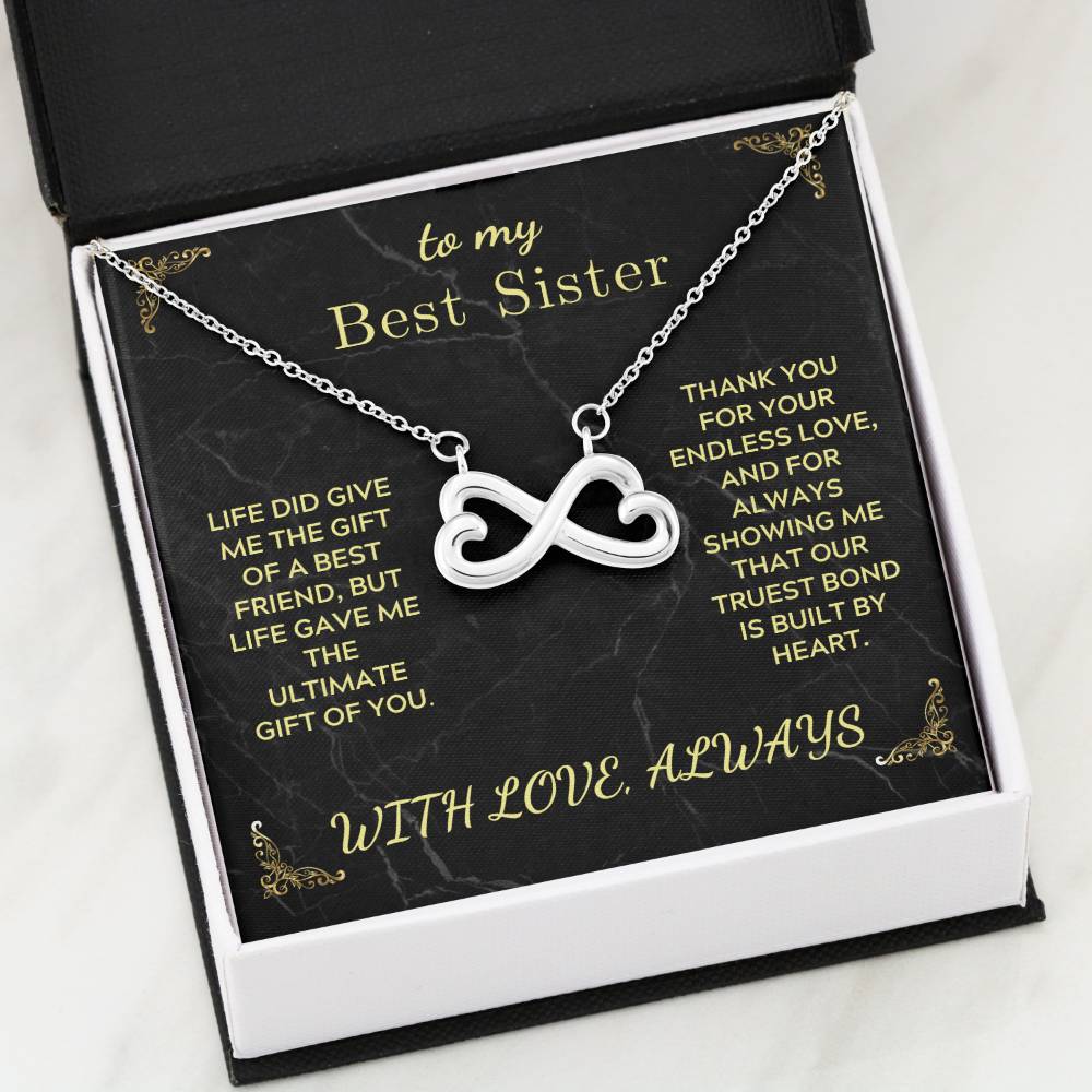 Infinity heart pendant necklace in open black gift box with “Best Sister” card