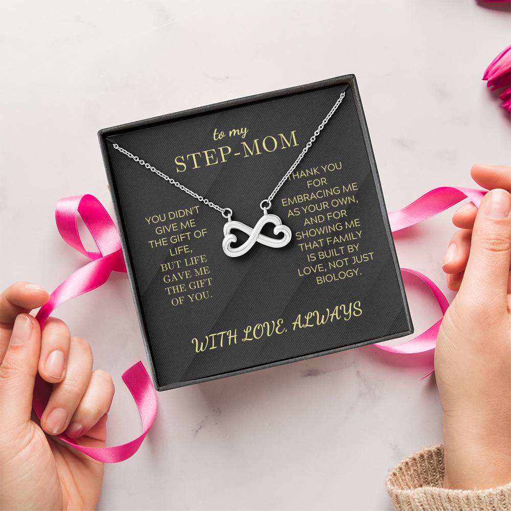 Silver infinity heart pendant necklace in a black gift box with pink ribbon and hands