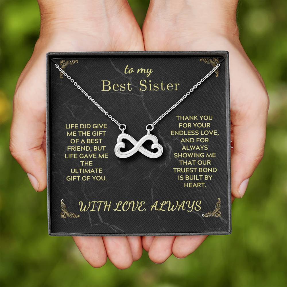 Infinity heart pendant necklace on black “Best Sister” gift card inside a box