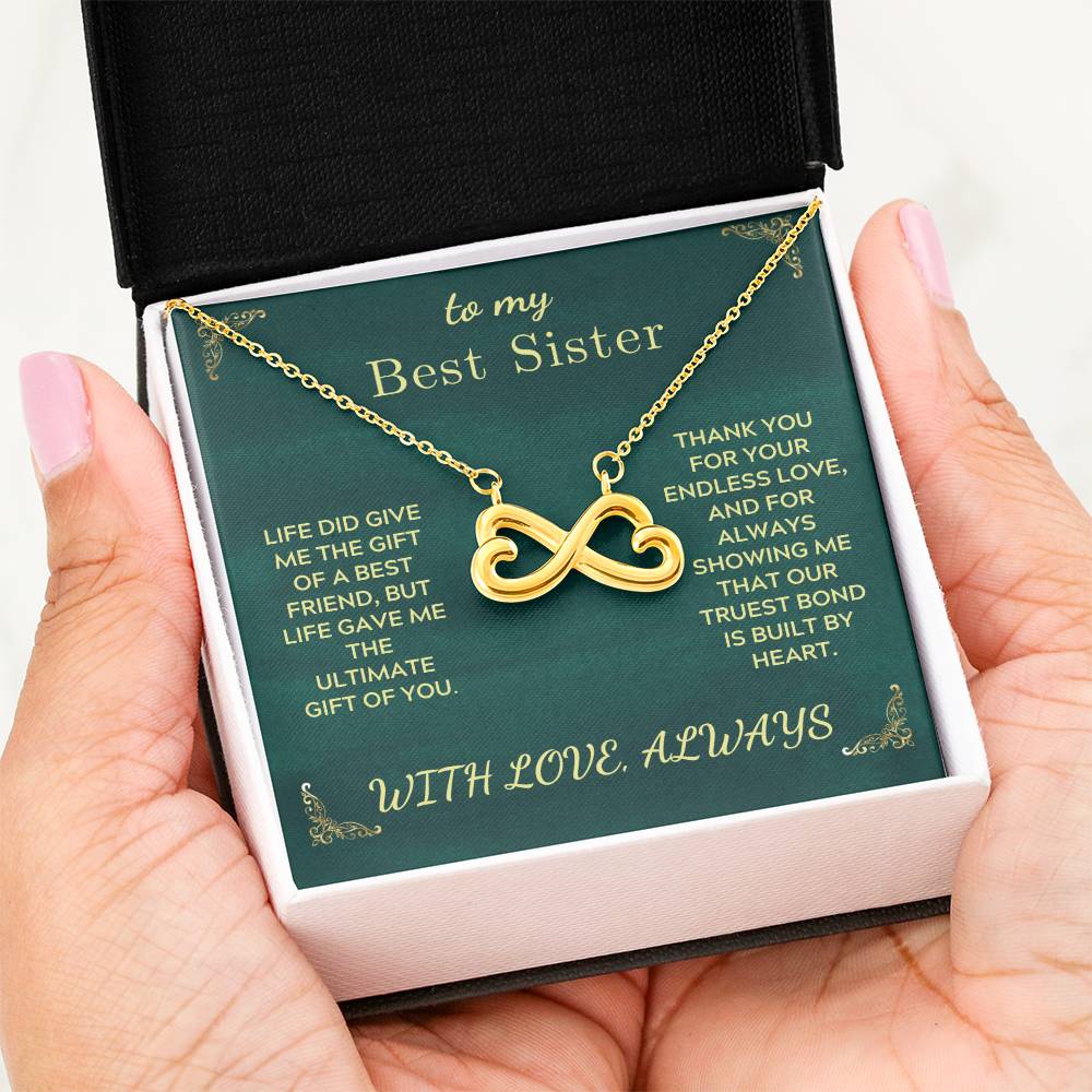 Green gift card box with gold heart infinity necklace in an open white case.