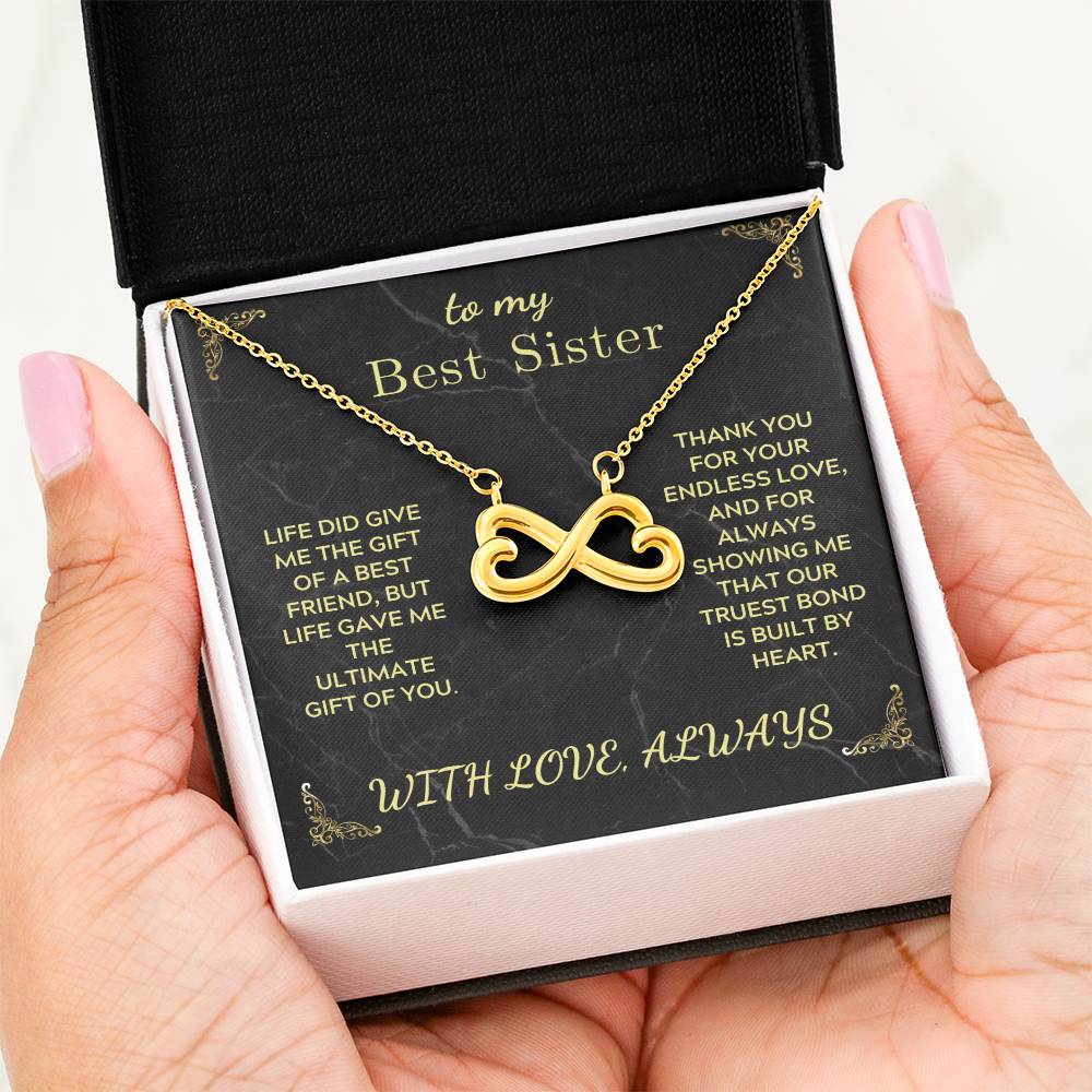 Gold-tone infinity heart pendant necklace in a black gift box on hand
