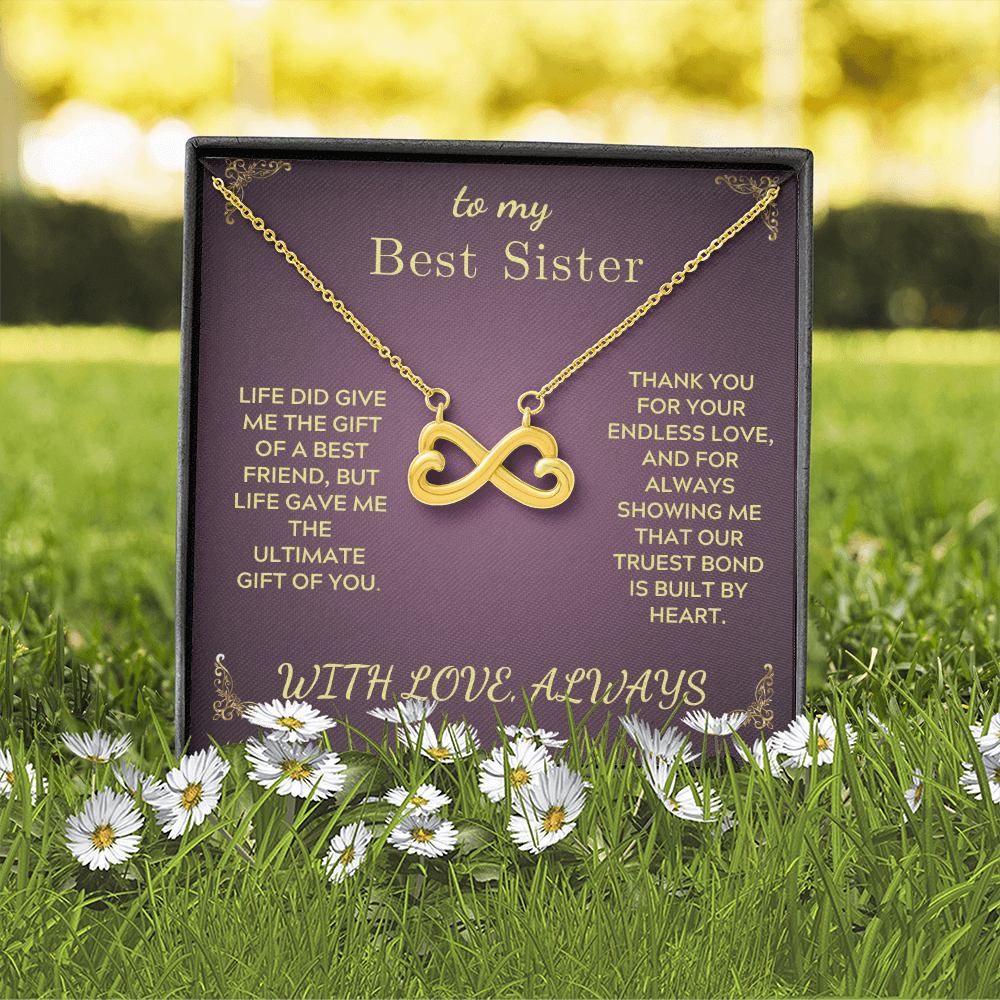 Gold heart-and-infinity pendant necklace displayed on purple gift box outdoors