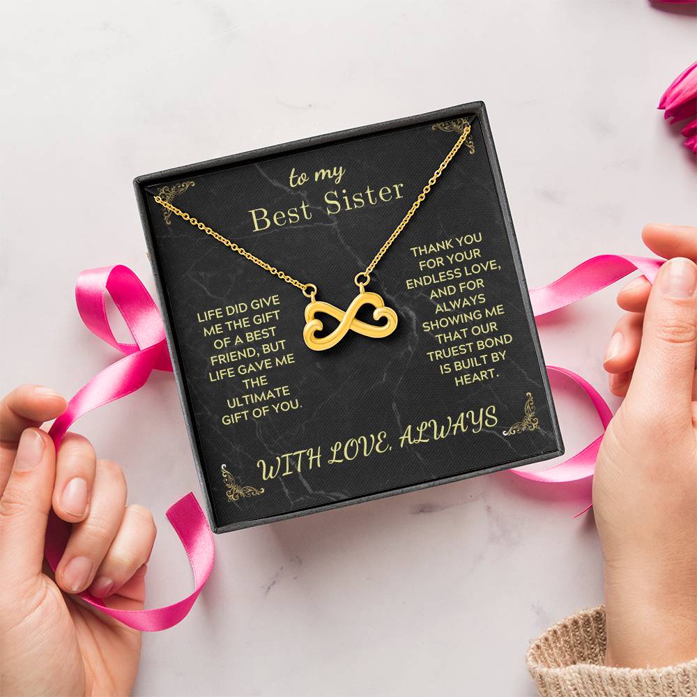 Gold-tone infinity heart pendant necklace on black “Best Sister” card in gift box