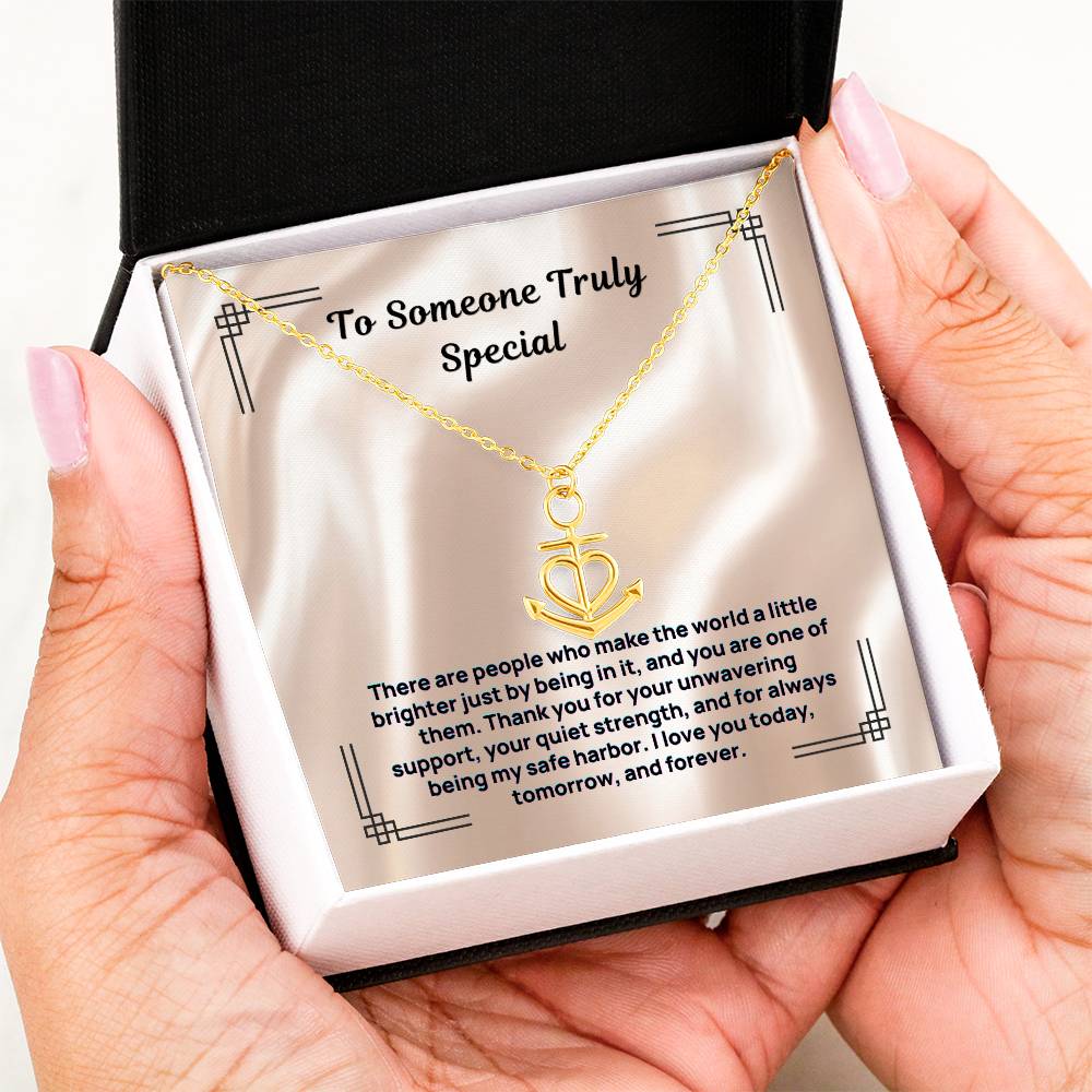 Gold anchor-and-heart pendant necklace held over open gift box