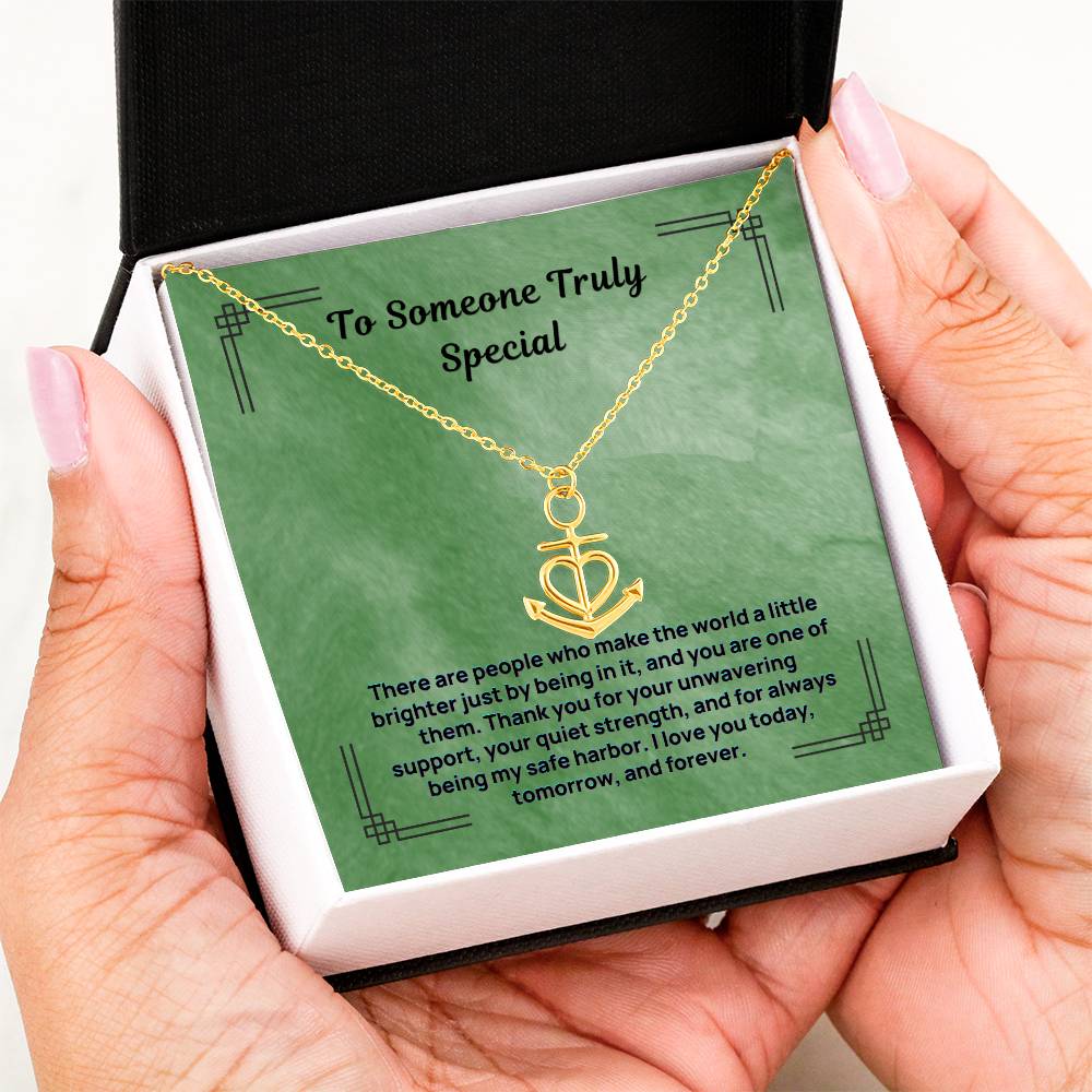 Gold anchor safe harbor pendant necklace held in hands, close-up