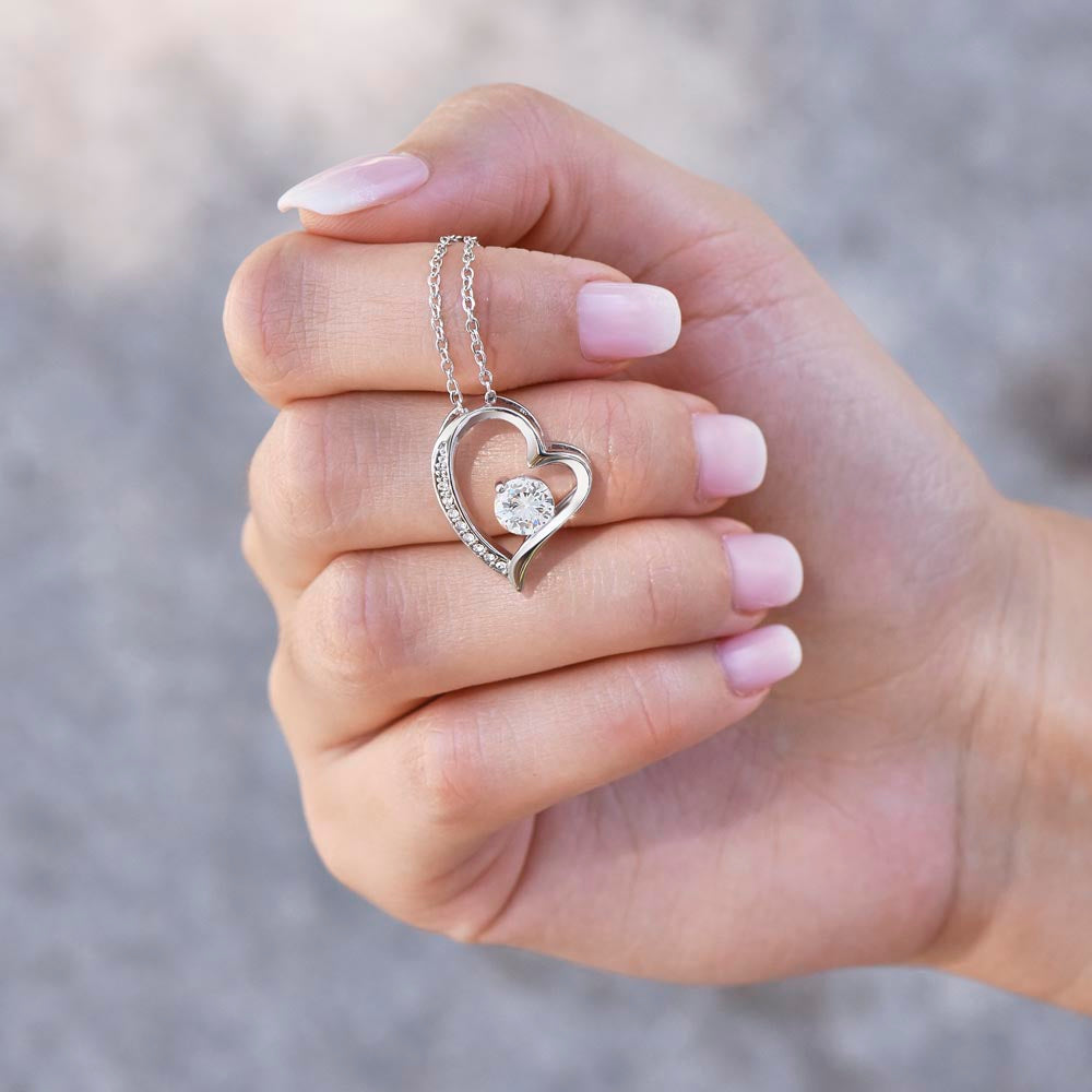Silver-tone heart pendant necklace with round crystal held in hand