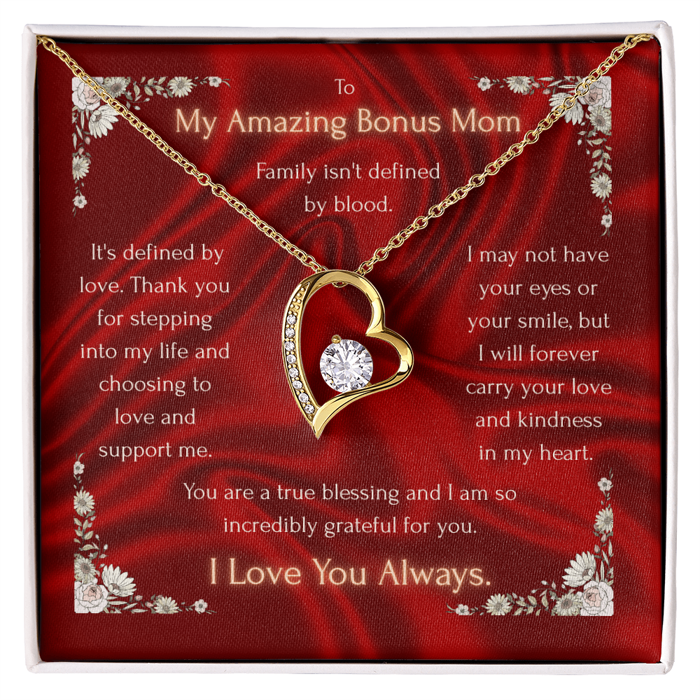 Heart pendant necklace with clear center stone on red card inside gold-trim gift box, gold tone.