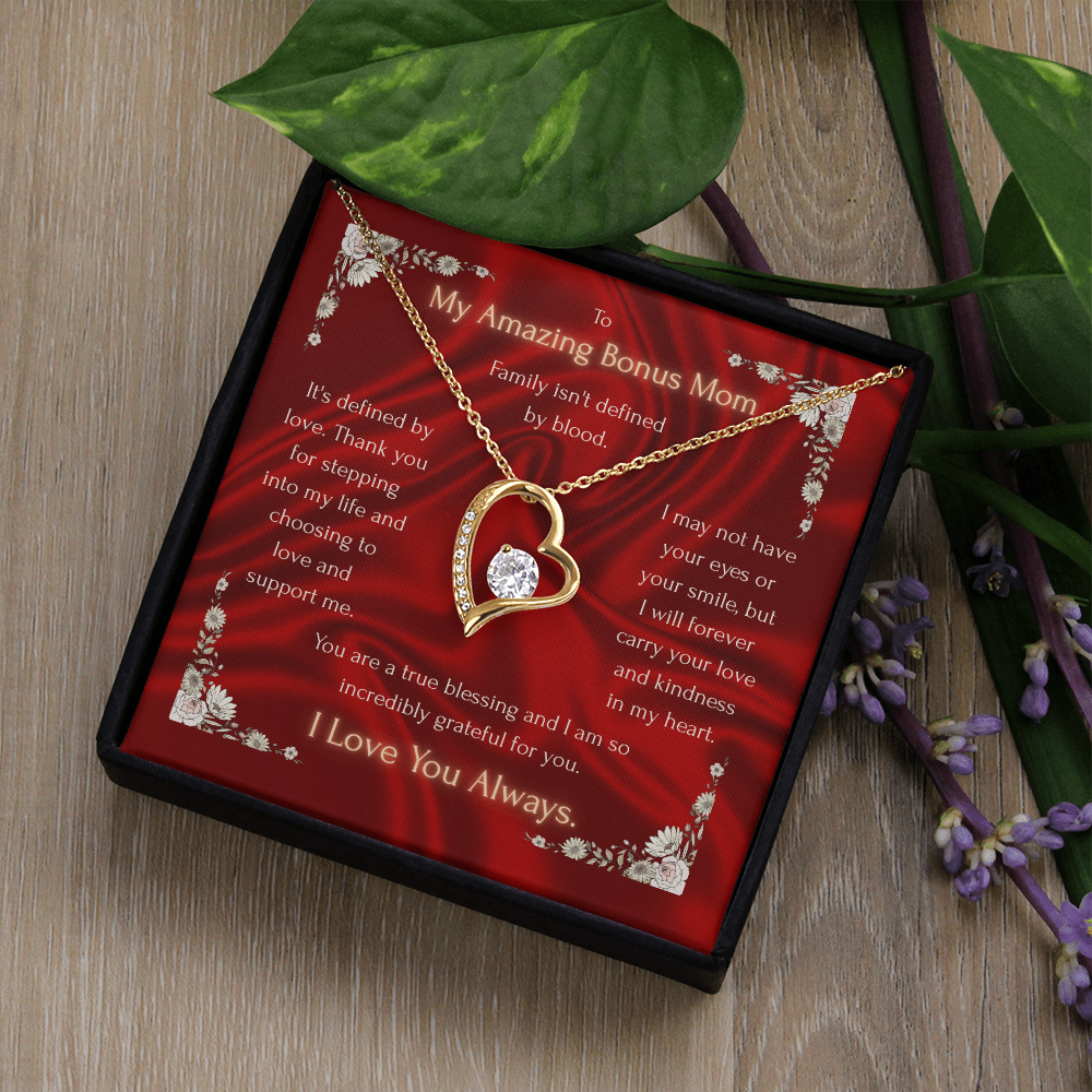 Gold heart pendant necklace on red floral card in black gift box, displayed on wood surface.