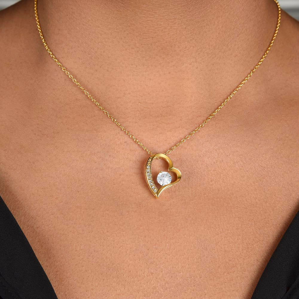 Gold heart pendant necklace with a clear center stone on a fine chain