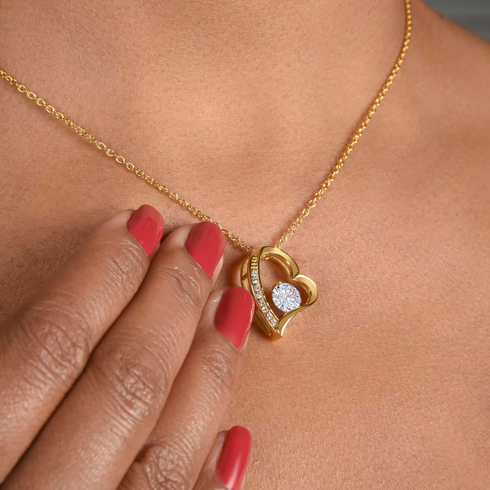 Gold-tone heart pendant necklace with embedded round stones and link chain, close-up.