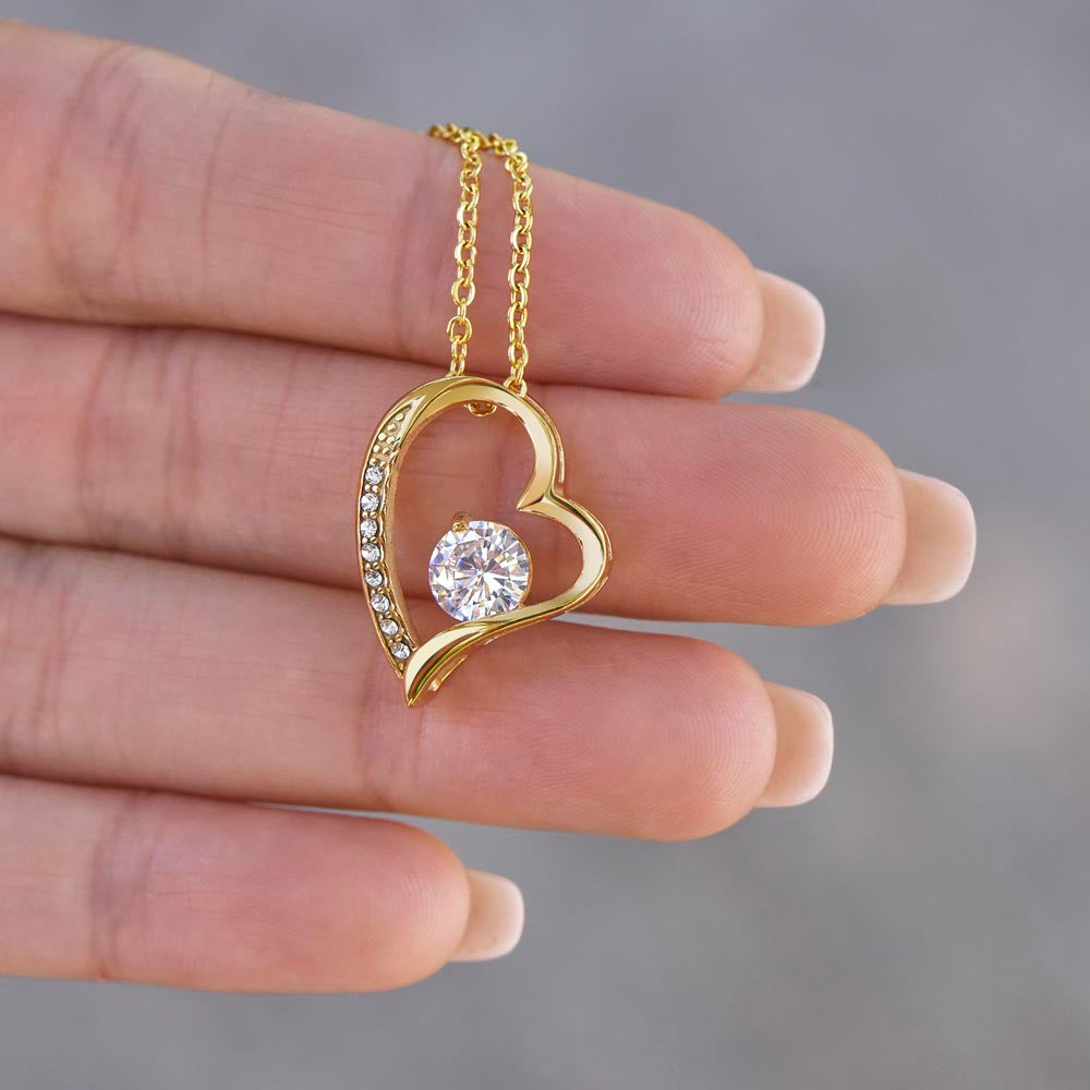 Gold heart pendant necklace with clear center stone and rhinestone border on chain