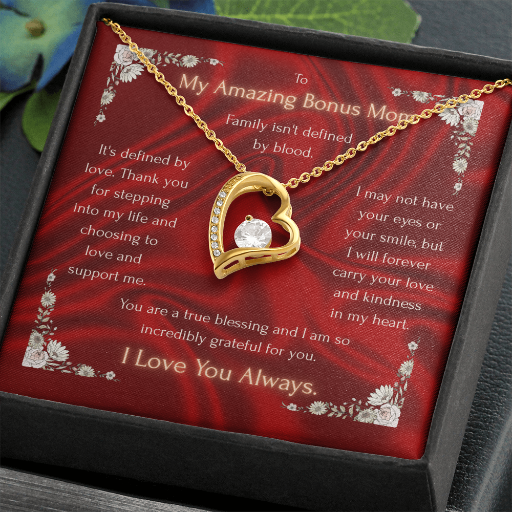 Heart pendant necklace with clear center stone over red card inside dark gift box, gold tone.