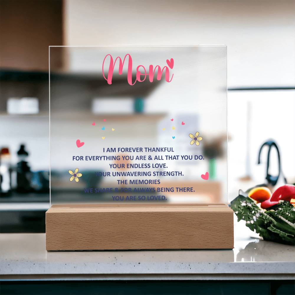 Clear acrylic “Mom” keepsake with heart and flower icons, on wood base