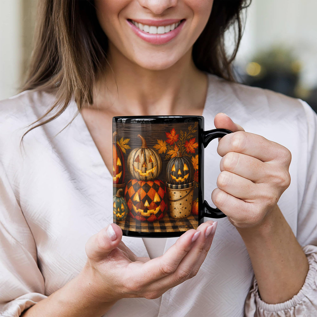 Black glossy ceramic coffee mug with jack-o'-lantern and leaf artwork, held in hand
