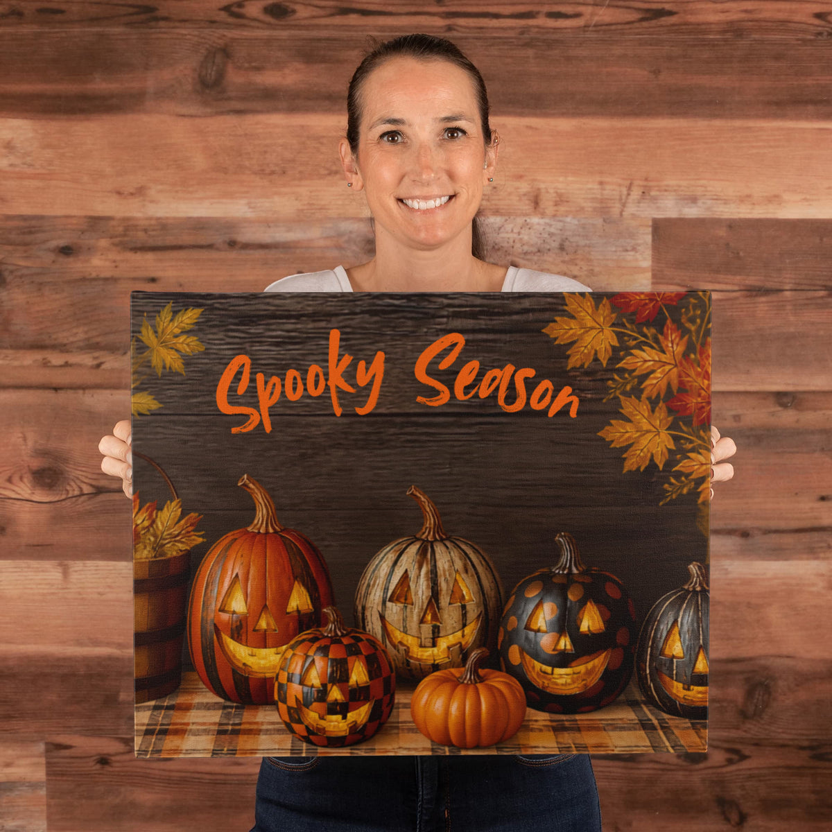Halloween canvas print held up: “Spooky Season” text over pumpkins, jack-o'-lanterns, and leaves.
